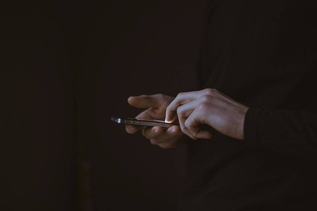 Mains d’une personne utilisant un smartphone, sans interface d’alarme identifiable