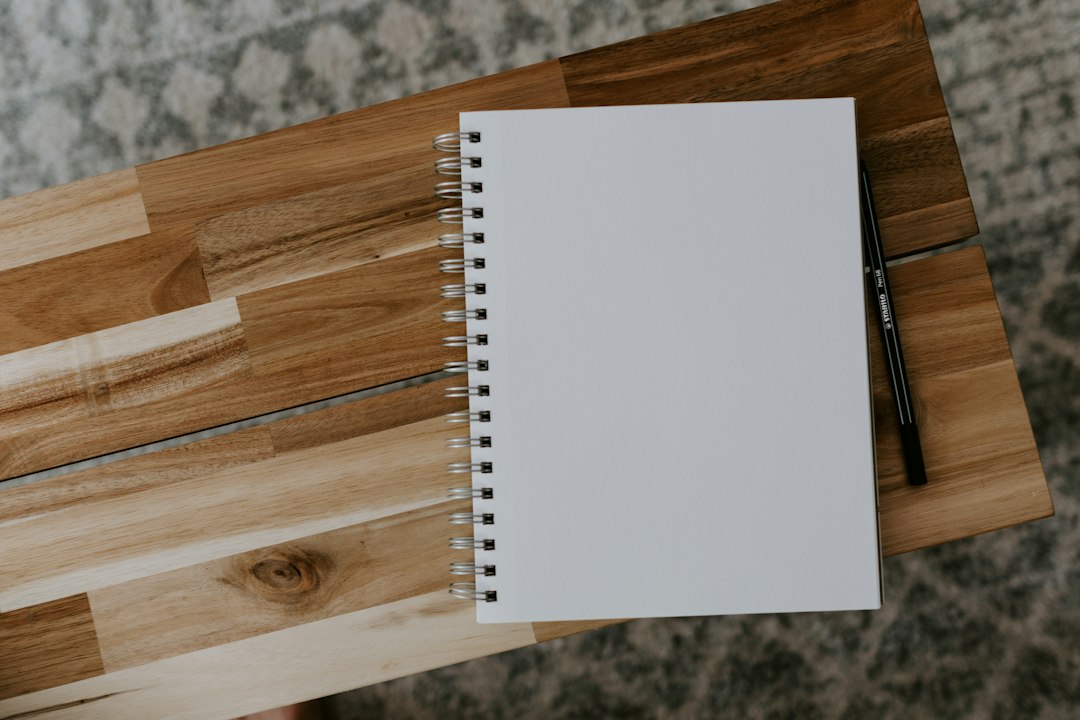 Carnet fermé et crayon posés sur une table en bois