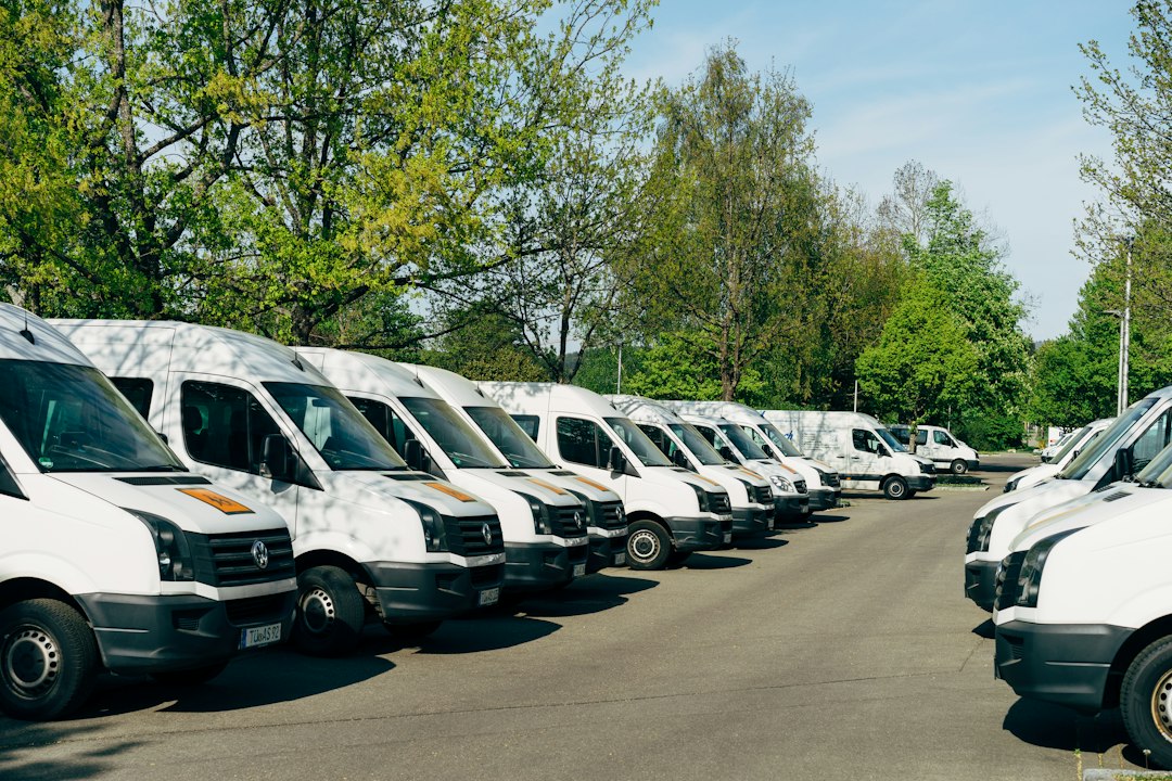 Plusieurs fourgons blancs stationnés sur un parking