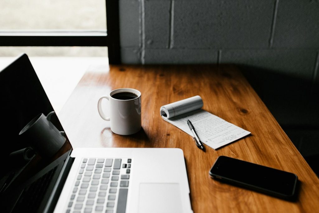 Carnet, téléphone et ordinateur posés sur une table