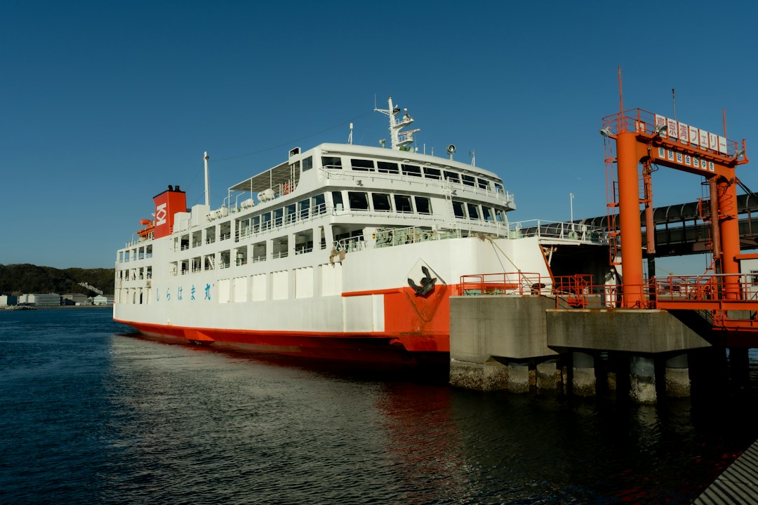 Ferry blanc et rouge à quai devant une passerelle d’embarquement