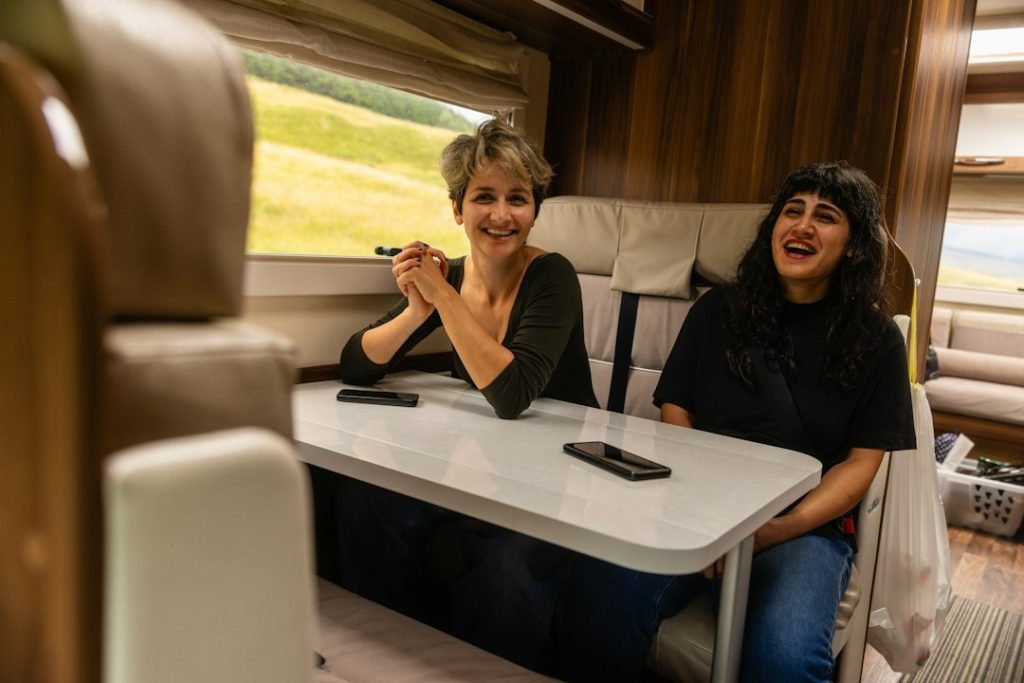 Deux personnes assises autour de la table dans la cellule d’un camping-car